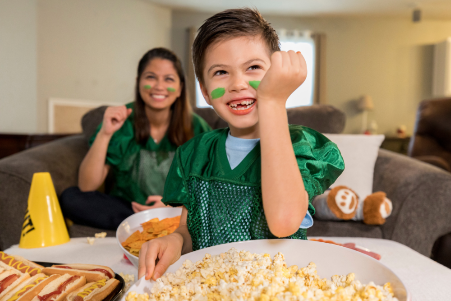Child cheering on team while eating popcorn